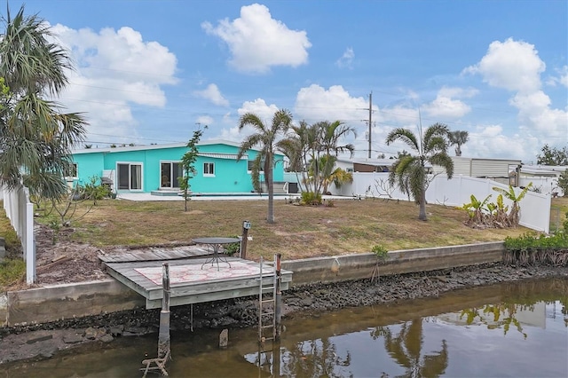 back of house with a lawn and a water view