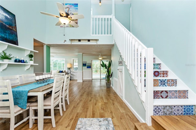 dining area featuring ceiling fan, light hardwood / wood-style floors, and a high ceiling