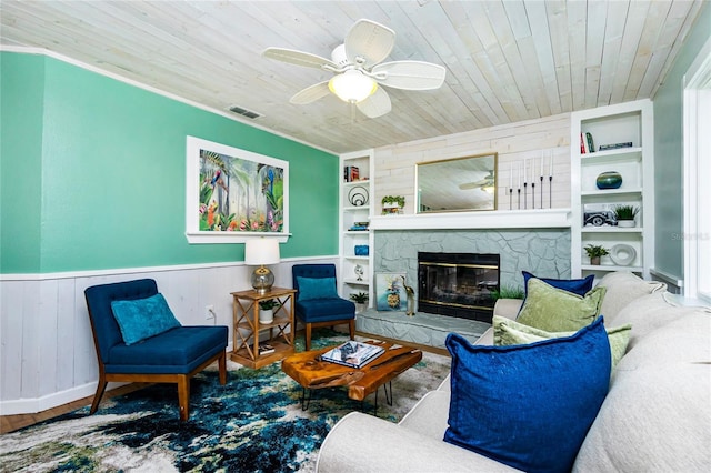 living room with a stone fireplace, wooden ceiling, built in features, and ceiling fan