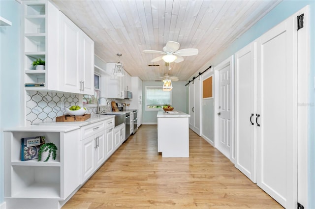 kitchen featuring white cabinetry, a center island, light hardwood / wood-style floors, wooden ceiling, and a barn door