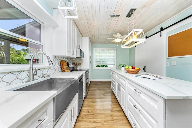 kitchen with pendant lighting, white cabinetry, a barn door, and wooden ceiling