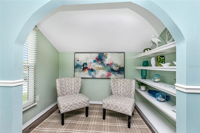 sitting room with lofted ceiling, hardwood / wood-style flooring, and a textured ceiling