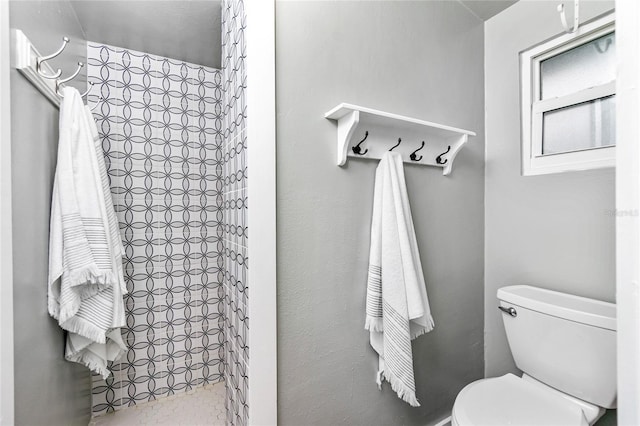 bathroom with a tile shower and toilet