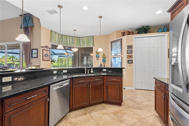 kitchen with dark stone counters, hanging light fixtures, sink, appliances with stainless steel finishes, and light tile patterned flooring