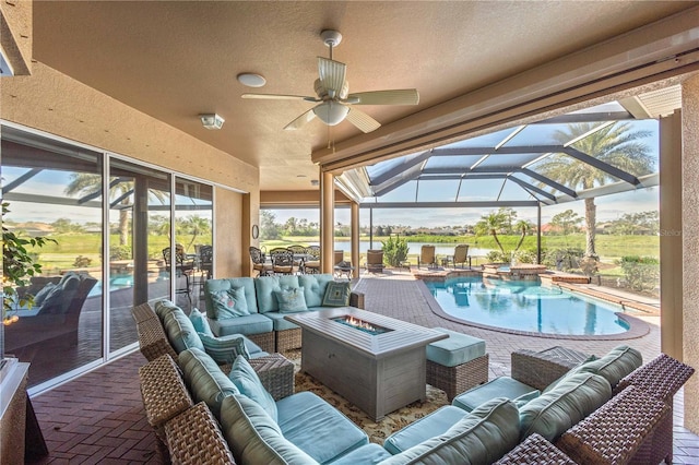 view of patio / terrace with glass enclosure, an outdoor living space with a fire pit, and ceiling fan