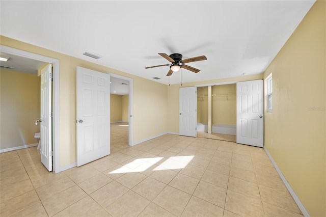 unfurnished bedroom featuring connected bathroom, ceiling fan, a closet, and light tile patterned floors