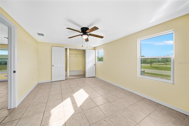 unfurnished bedroom with ceiling fan, light tile patterned floors, multiple windows, and a closet