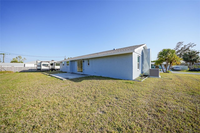 rear view of house featuring cooling unit, a patio area, and a lawn