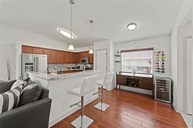 kitchen featuring wine cooler, dark wood-type flooring, light stone counters, hanging light fixtures, and stainless steel appliances