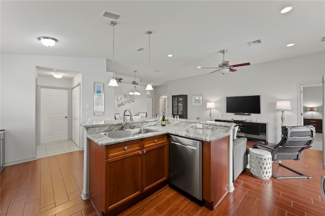 kitchen with sink, dishwasher, a kitchen island with sink, hanging light fixtures, and light stone countertops