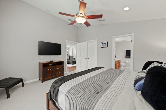 bedroom featuring ceiling fan, lofted ceiling, light carpet, and ensuite bath