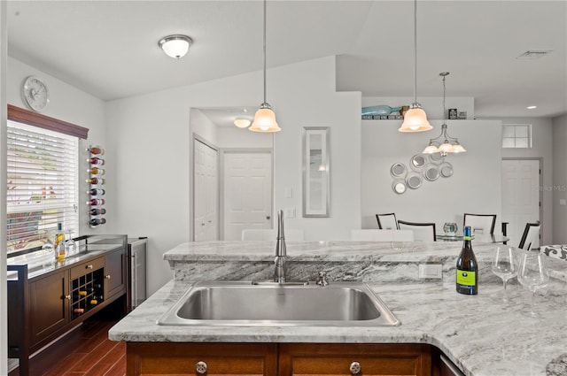 kitchen featuring dark hardwood / wood-style floors, an island with sink, lofted ceiling, sink, and hanging light fixtures