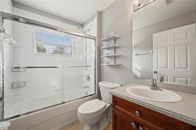 full bathroom featuring vanity, combined bath / shower with glass door, and toilet