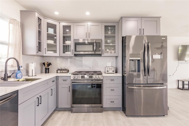 kitchen with gray cabinets, sink, light hardwood / wood-style floors, and stainless steel appliances