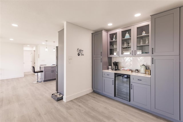 bar with decorative backsplash, light wood-type flooring, decorative light fixtures, gray cabinets, and wine cooler