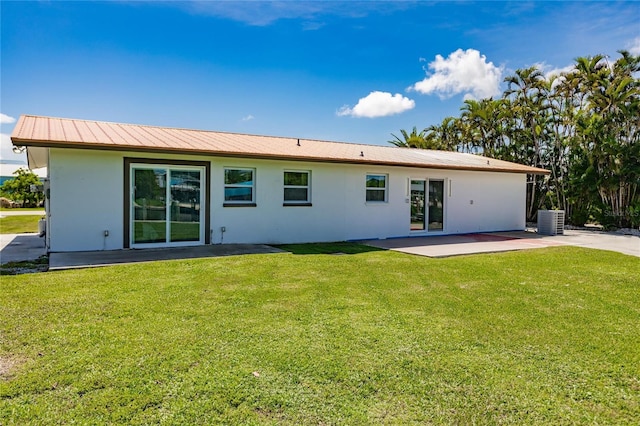 rear view of property with cooling unit, a patio area, and a lawn