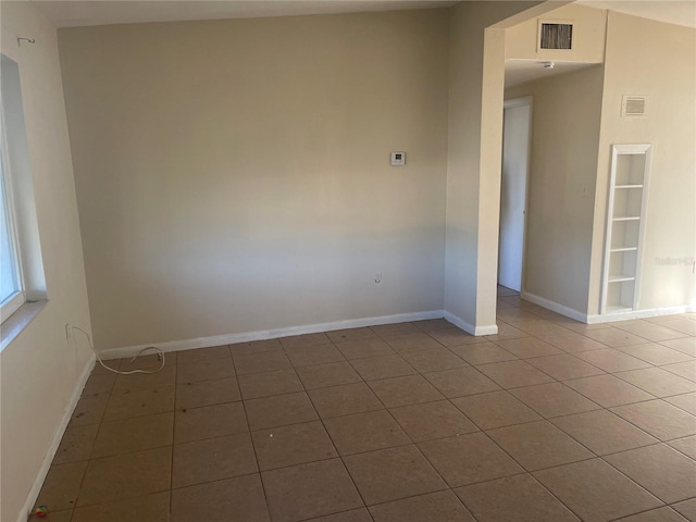 tiled spare room featuring built in shelves