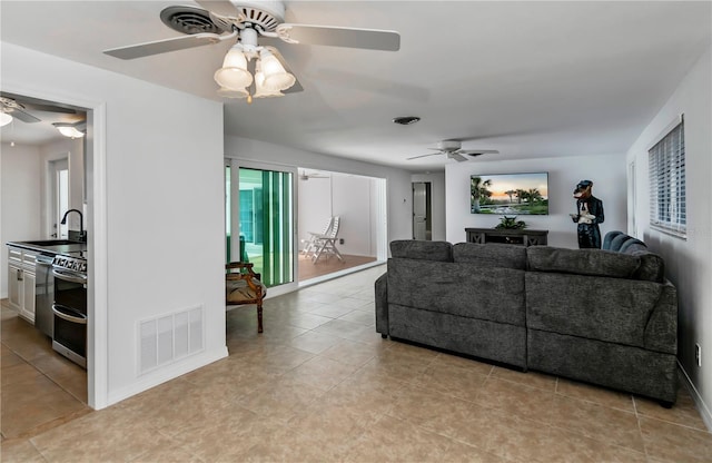 tiled living room with ceiling fan, a wealth of natural light, and sink