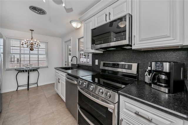 kitchen featuring appliances with stainless steel finishes, white cabinetry, sink, a chandelier, and light tile patterned floors