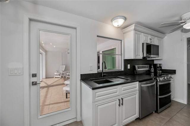 kitchen with light tile patterned floors, ceiling fan, stainless steel appliances, white cabinets, and sink