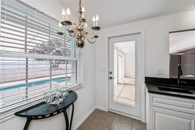 doorway to outside featuring light tile patterned flooring, a chandelier, and sink