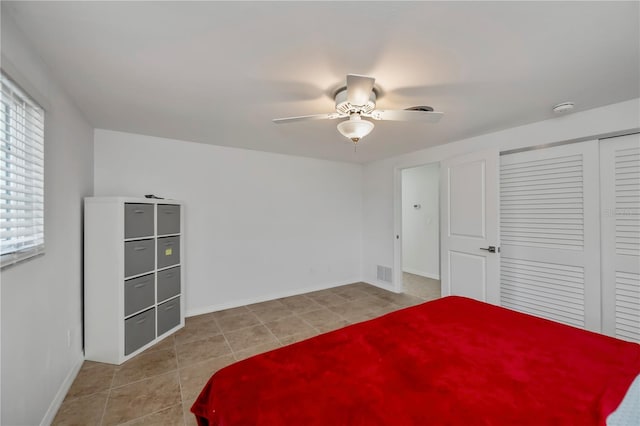 bedroom featuring ceiling fan, light tile patterned floors, and a closet