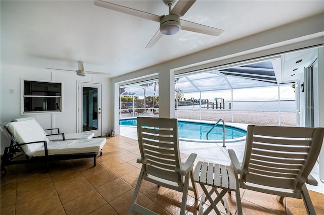 view of swimming pool featuring glass enclosure, ceiling fan, and a patio