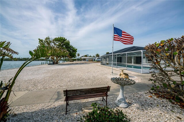 view of community featuring a swimming pool, a water view, and a patio