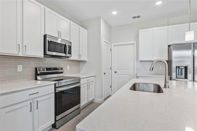 kitchen featuring sink, decorative light fixtures, white cabinets, and appliances with stainless steel finishes