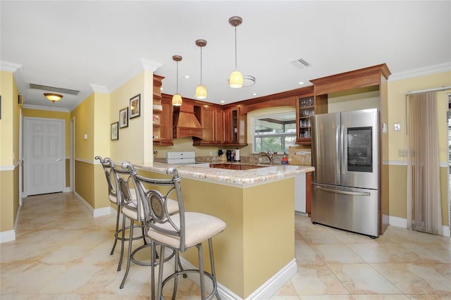 kitchen with light stone countertops, decorative light fixtures, stainless steel fridge, kitchen peninsula, and crown molding