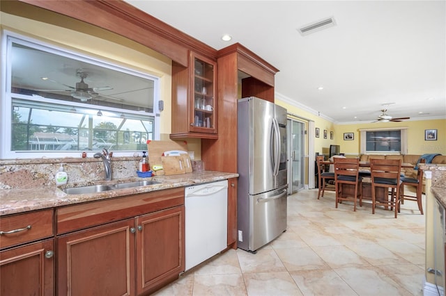 kitchen featuring light stone countertops, dishwasher, sink, stainless steel fridge, and ornamental molding