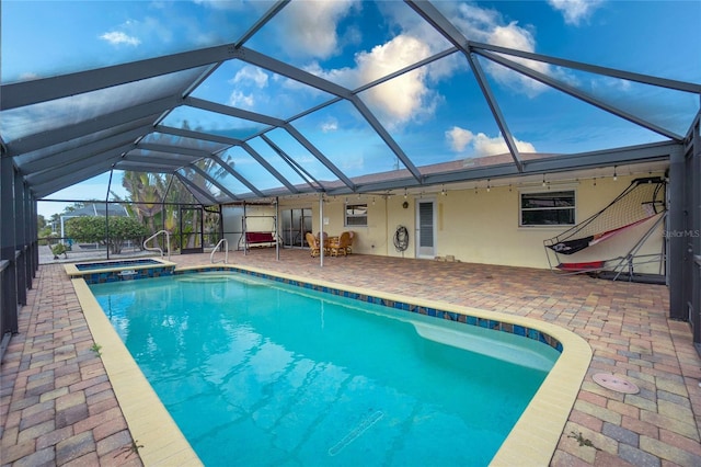 view of pool featuring a patio area, glass enclosure, and an in ground hot tub