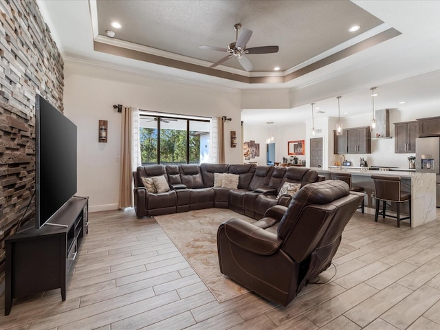 living room with ceiling fan, ornamental molding, and a tray ceiling