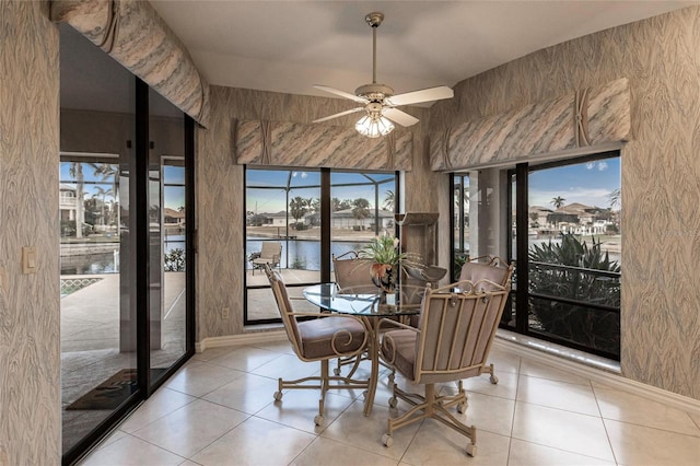 tiled dining area with a water view and ceiling fan