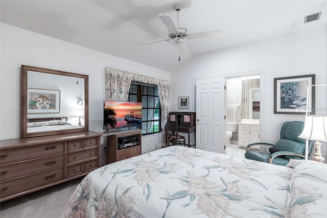 bedroom with ensuite bath, ceiling fan, light colored carpet, and vaulted ceiling