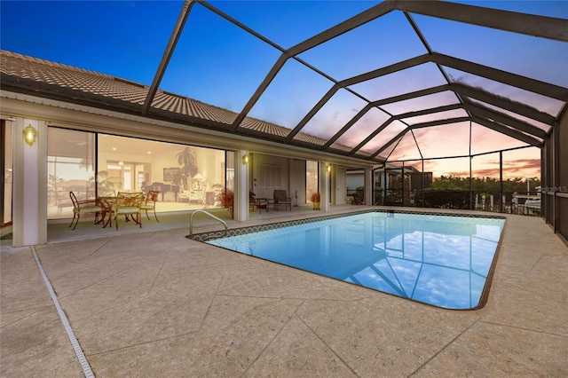 pool at dusk featuring a patio and glass enclosure