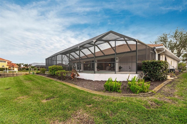 rear view of house featuring glass enclosure and a yard