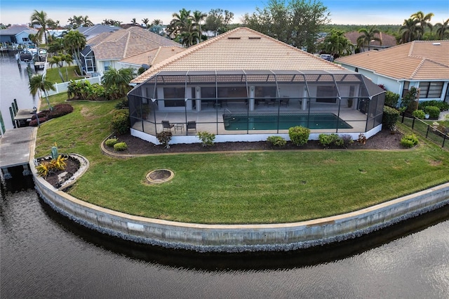 back of property featuring a lawn, glass enclosure, and a water view