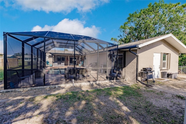 rear view of property featuring glass enclosure and a patio area