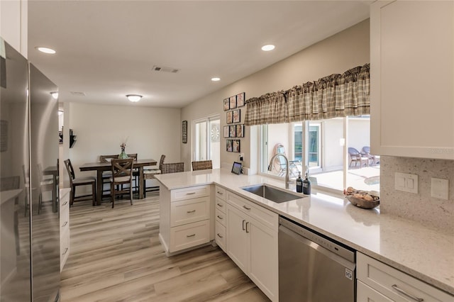 kitchen featuring kitchen peninsula, appliances with stainless steel finishes, white cabinetry, and sink