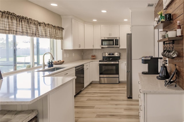 kitchen featuring sink, white cabinetry, stainless steel appliances, and light hardwood / wood-style flooring