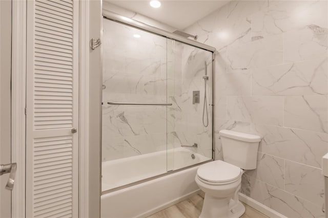 bathroom with shower / bath combination with glass door, wood-type flooring, and toilet