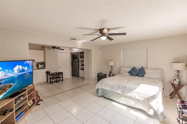 bedroom featuring light tile patterned floors, a textured ceiling, a closet, and ceiling fan