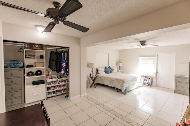 tiled bedroom featuring ceiling fan, a textured ceiling, and a closet