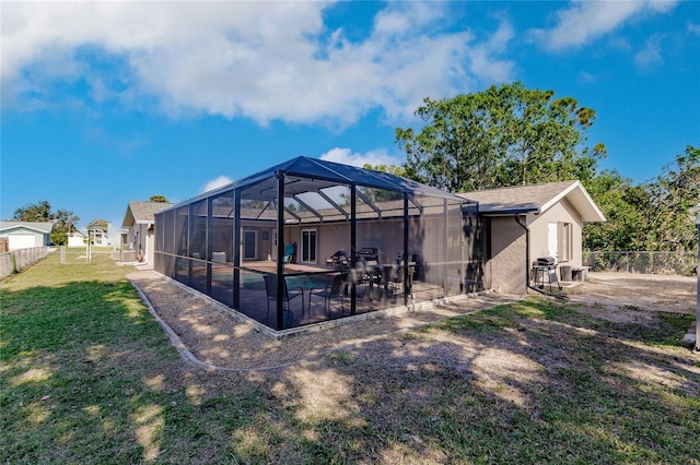 rear view of house featuring a lawn, glass enclosure, and a patio area