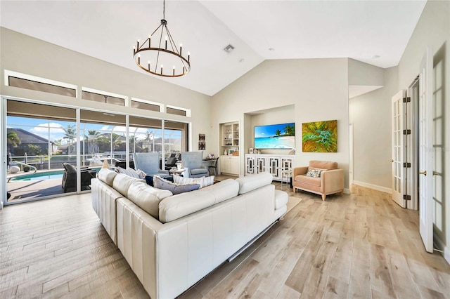 living room featuring french doors, light wood-type flooring, high vaulted ceiling, and an inviting chandelier