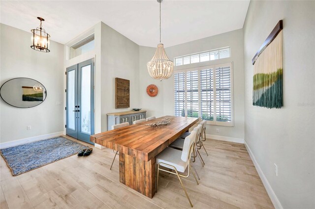 dining area featuring french doors, light hardwood / wood-style flooring, and a notable chandelier