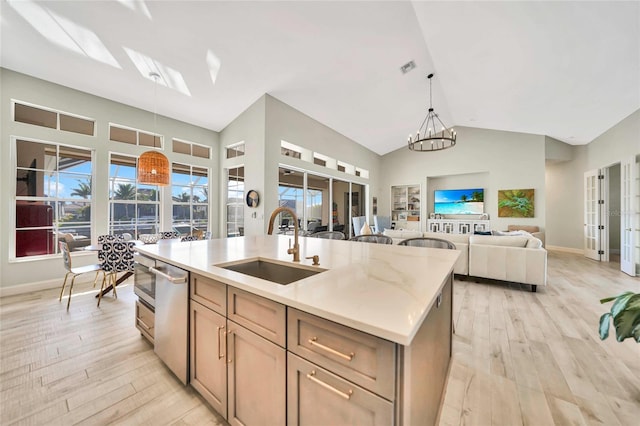 kitchen with sink, hanging light fixtures, a notable chandelier, an island with sink, and light brown cabinetry