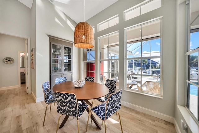 dining space with light hardwood / wood-style floors and a high ceiling