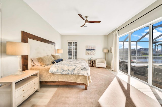 bedroom with access to exterior, a water view, light hardwood / wood-style flooring, and ceiling fan